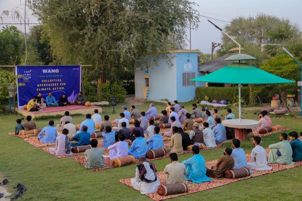 Outdoor community gathering for collective climate action at WANG event in Lasbela garden with solar infrastructure