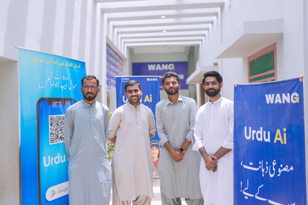 WANG team members standing at WALI lab entrance with Urdu AI banners